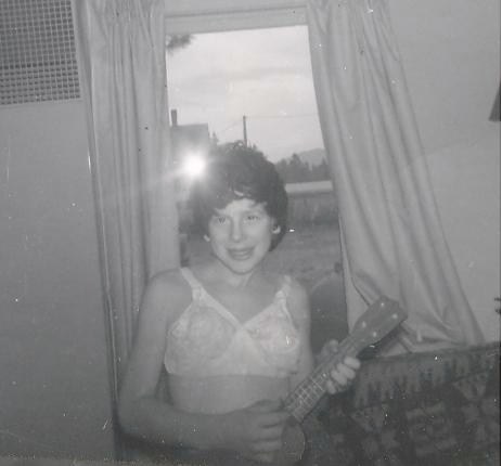 Rusty wearing grandma's wig and bra playing an ukelele